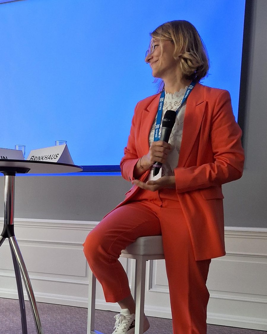 Yvonne Brinkhaus im orangen Anzug bei einem Vortrag auf der Bühne